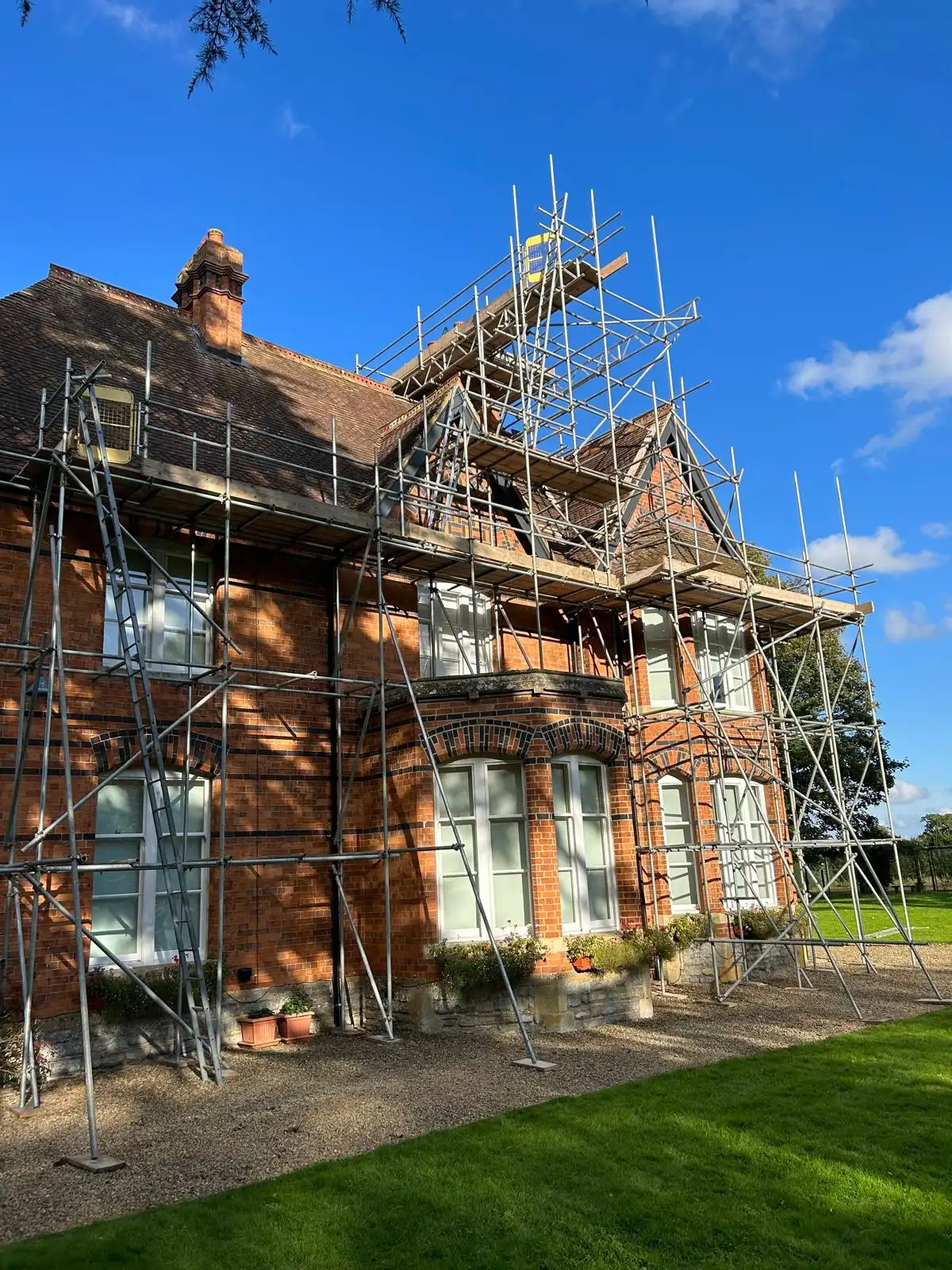 Scaffolding around a red-brick house for roof work